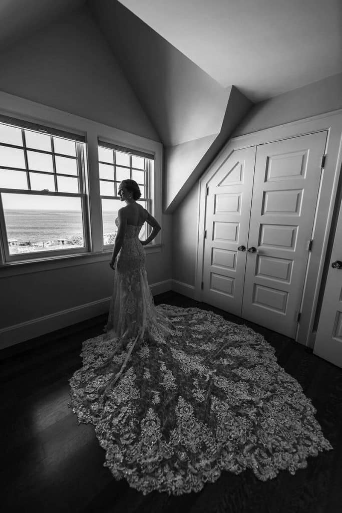 Silhouette of a bride standing beside a large window in an attic-style room