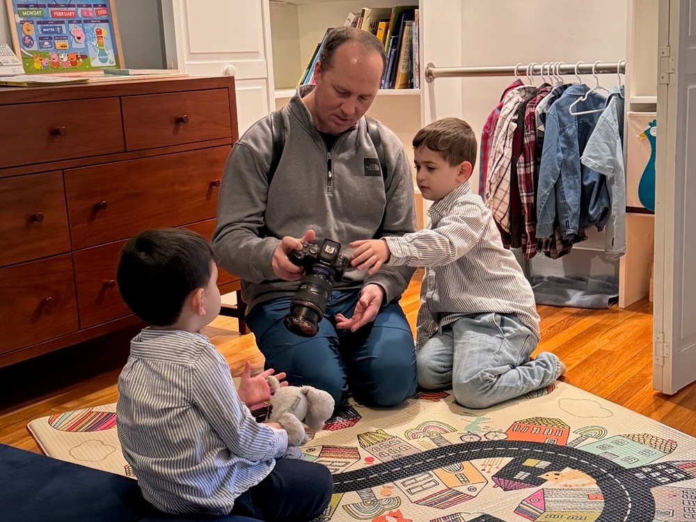 Behind-the-scenes photo of a photographer crouching to photograph two young boys playing indoors