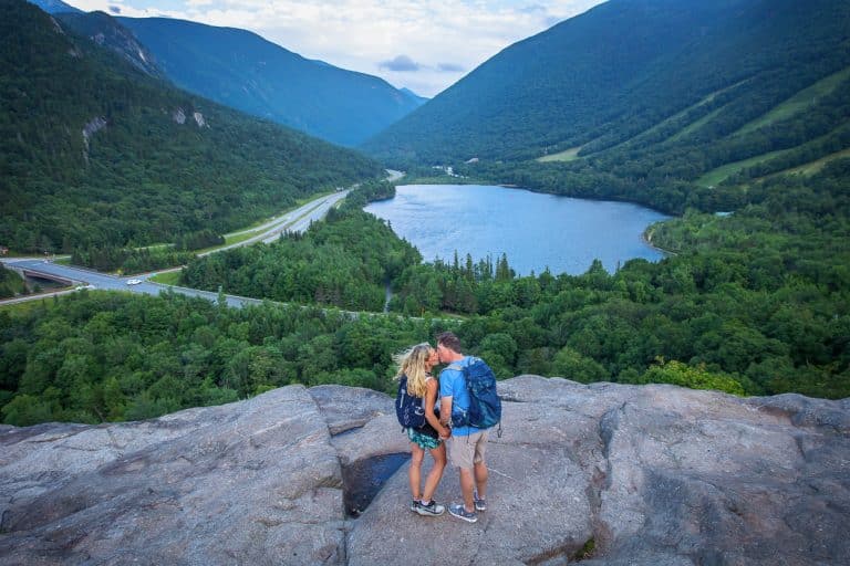 Couple kissing on a rocky mountain overlook above a lake