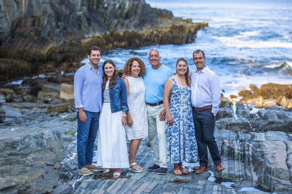 Family standing together on a rocky ocean shoreline for a portrait